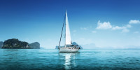 Lean sailboat in blue, protected waters with just the mainsail up