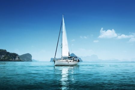 Lean sailboat in blue, protected waters with just the mainsail up