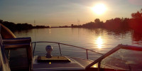 Sunset in calm waters from a boat with small outboard motor