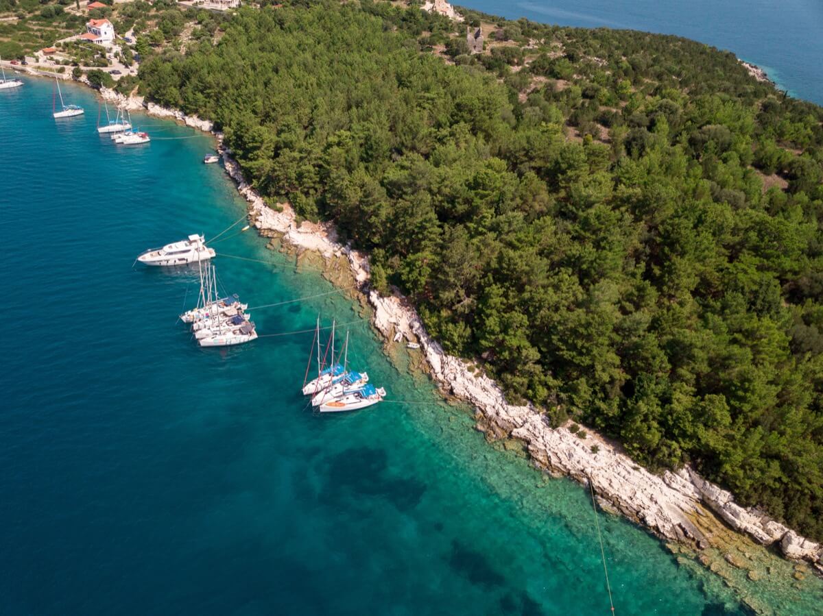 Ten sailboats anchored at island shore