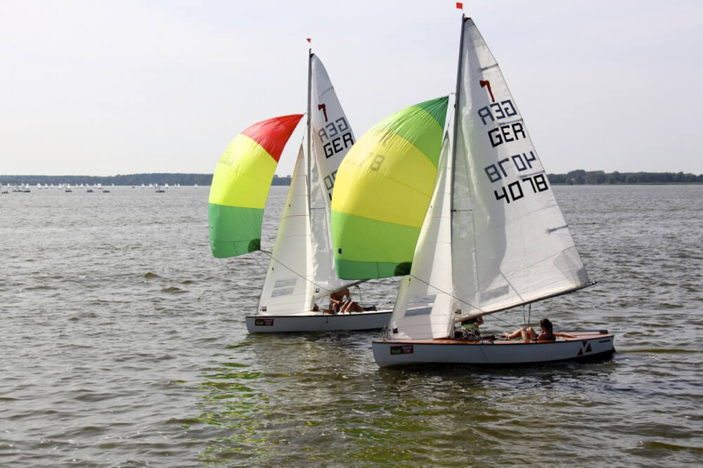Small sloops using colorful gennakers in grey water