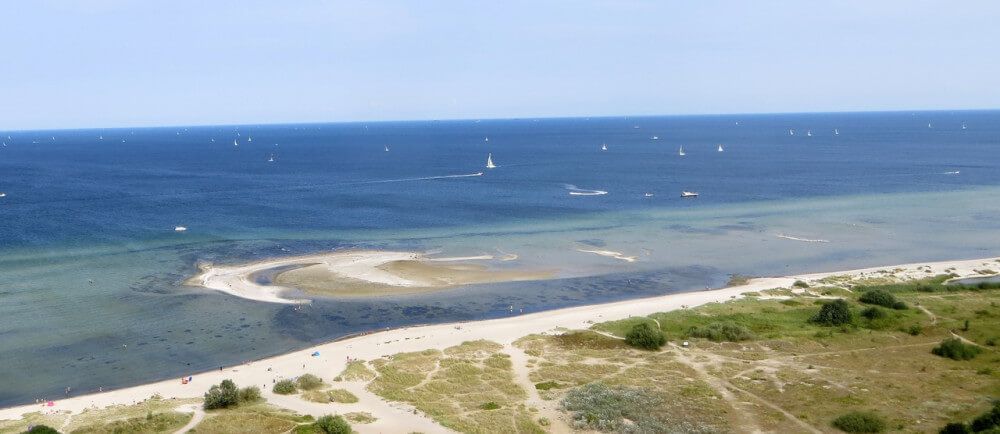 Birdseye view of beach and coastline with lots of small sailboats