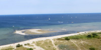 Birdseye view of beach and coastline with lots of small sailboats