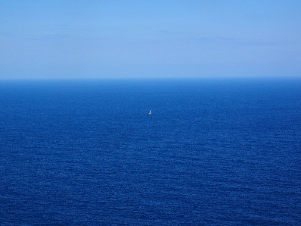 Small sailboat in middle of huge blue sea