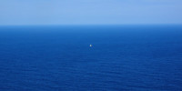 Small sailboat in middle of huge blue sea