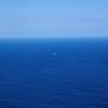 Small sailboat in middle of huge blue sea