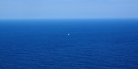 Small sailboat in middle of huge blue sea