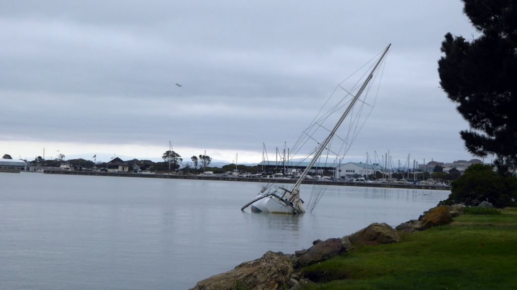 Sailboat half sunk under grey sky