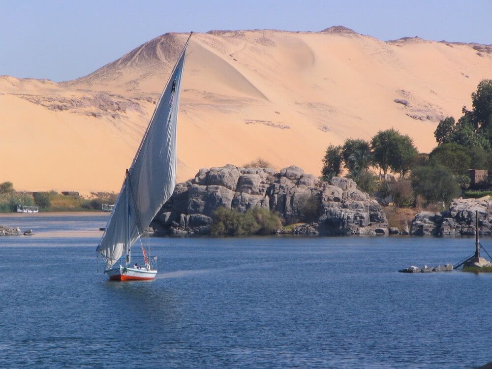 Sailboat in coastal waters with desert hill in the background