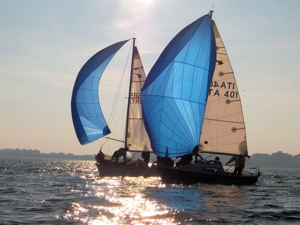 Italian sailboats with blue sails competing in sunny weather