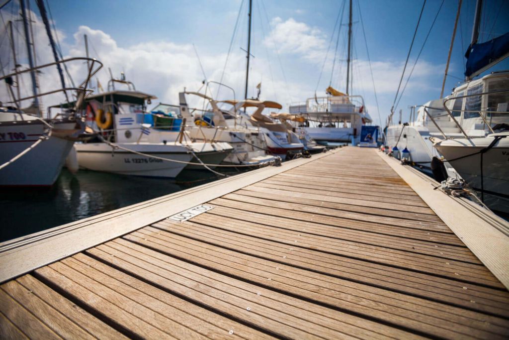 Wooden boardwalk in marina with boats tied up on either side