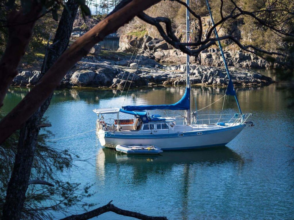 Sailboat with tender in rocky bay