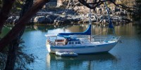 Sailboat with tender in rocky bay