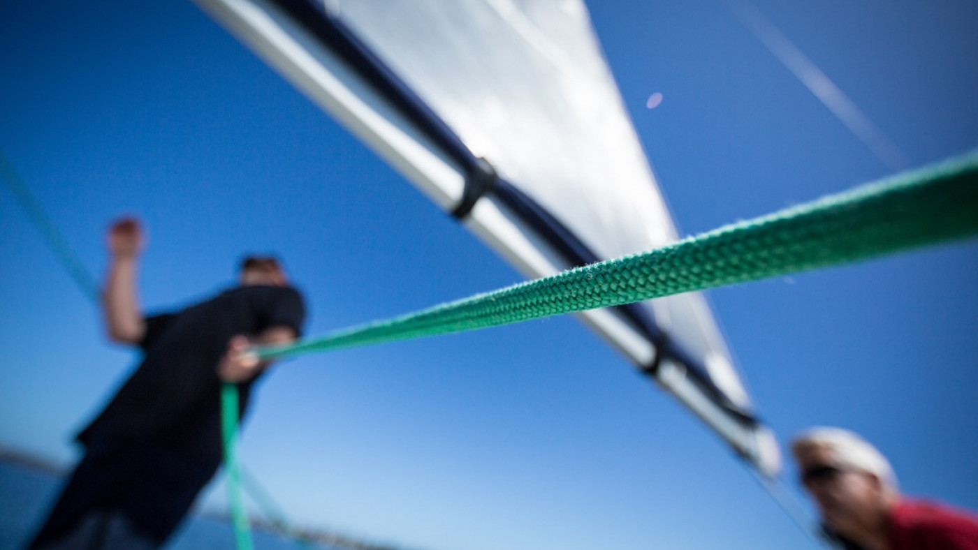 Man on sailboat holding green line