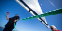 Man on sailboat holding green line