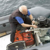 Old man works on boat engine