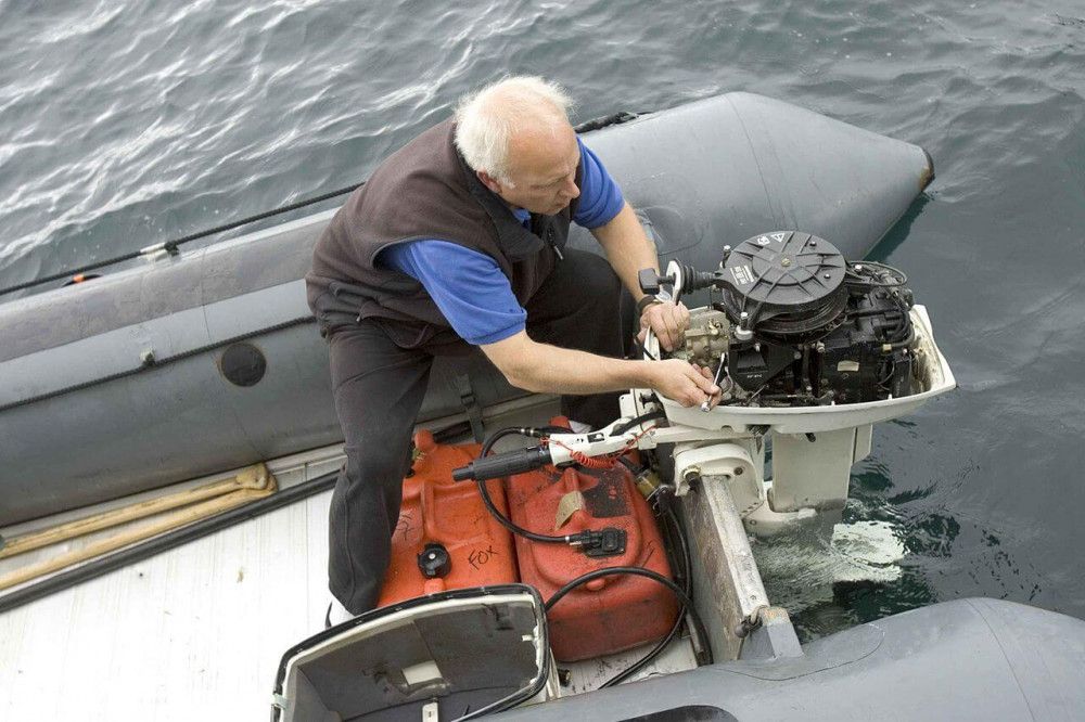 Old man works on boat engine