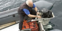 Old man works on boat engine