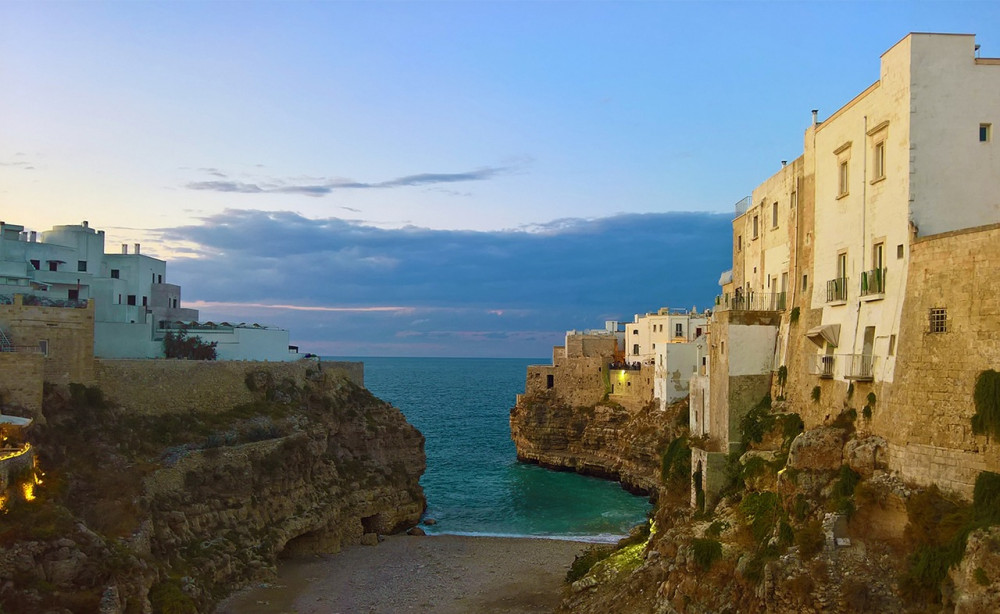 Small bay with tall white buildings on cliffs at sunset